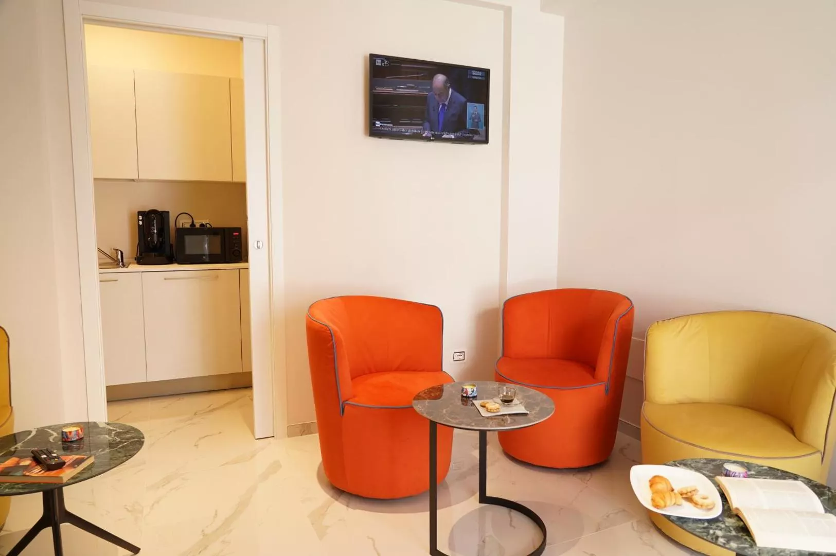 La sala comune con poltroncine arancioni e angolo cucina