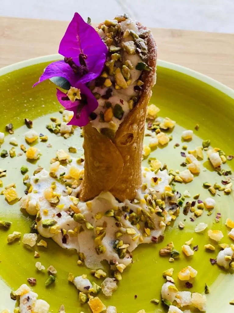 Un cannolo con granella di pistacchio e fiori